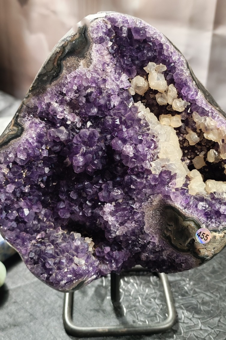 Vue de face de la géode d’améthyste sur socle proposée à la vente. Cristallisation violette, formations blanches et bandes minérales visibles sur le pourtour. Poids annoncé : 3,920 kg.