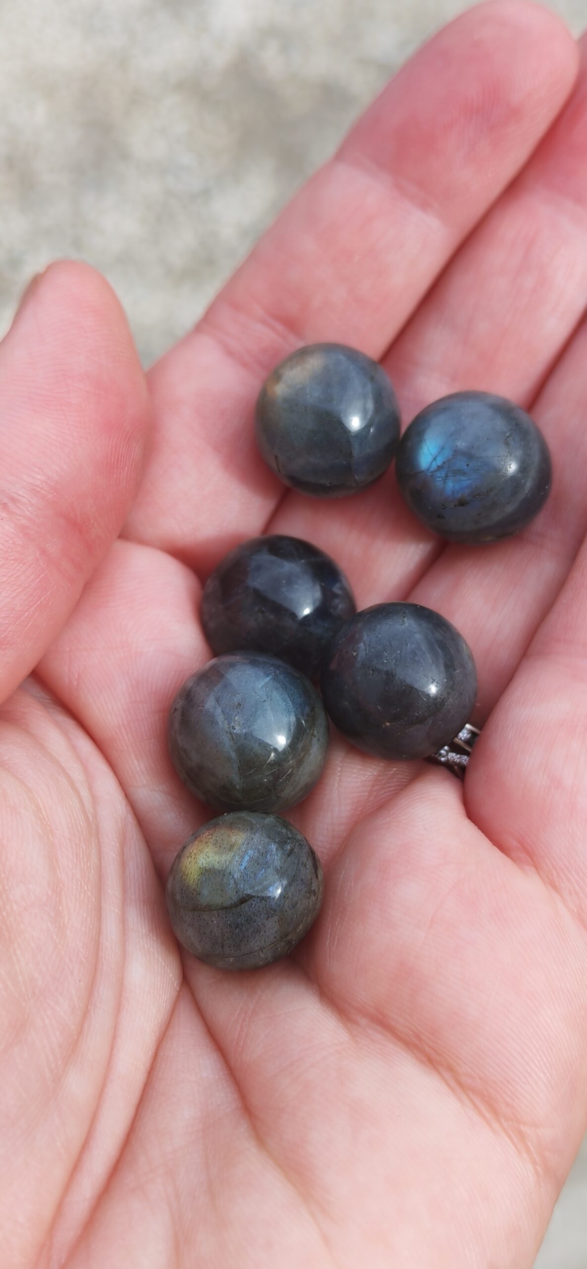 bille de labradorite beleue dorée dans les mains, vu du dessus 1.5cm présentation