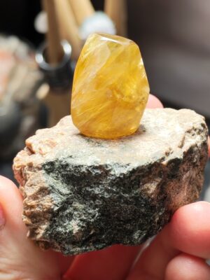Face jaune translucide de la fluorite repolie sur une matrice brute, photographiée en intérieur