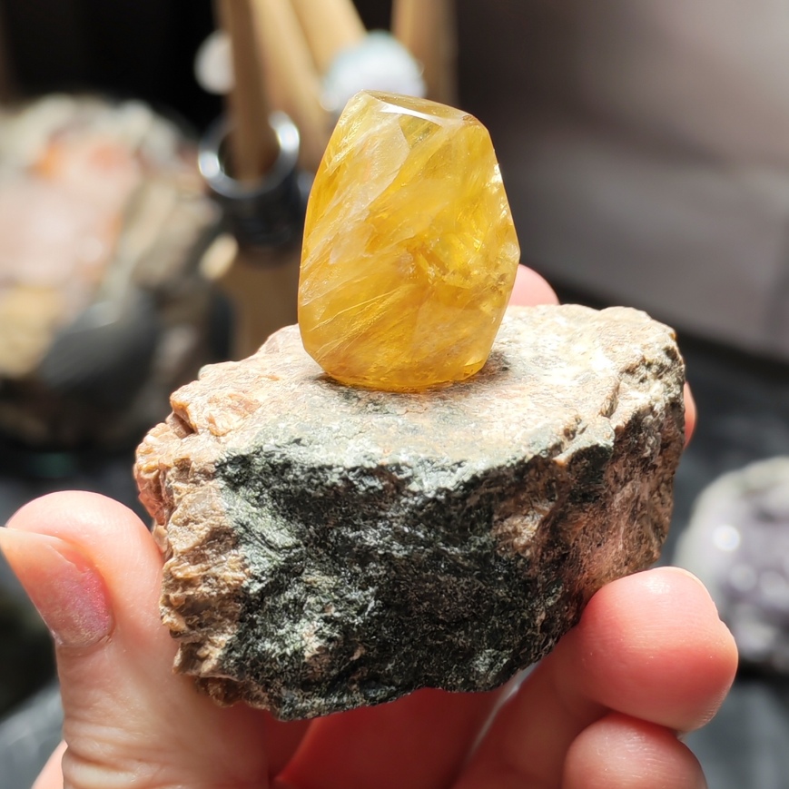 Face jaune translucide de la fluorite repolie sur une matrice brute, photographiée en intérieur