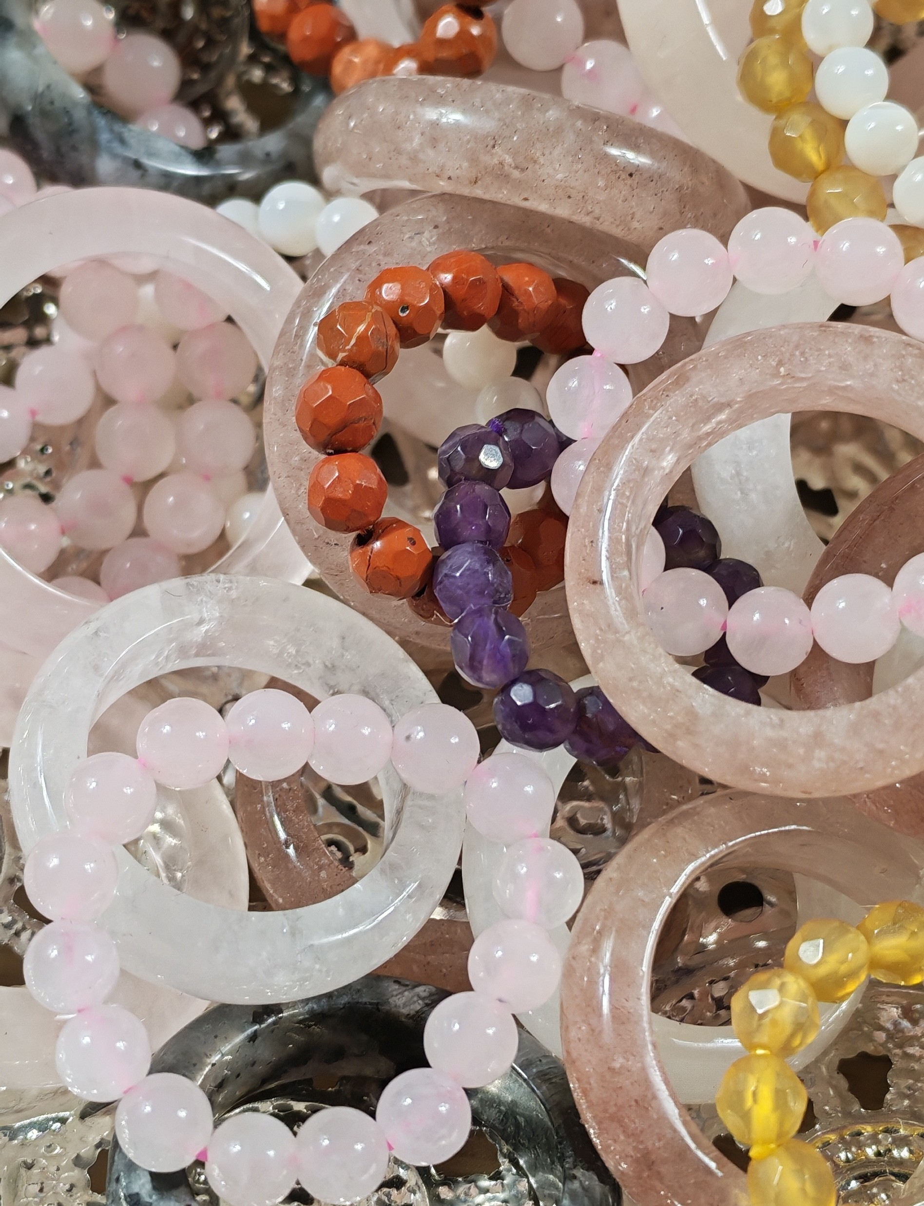 Bagues joncs et bagues en perles roses, blanches, violettes, orangées et jaunes sur un plateau argenté