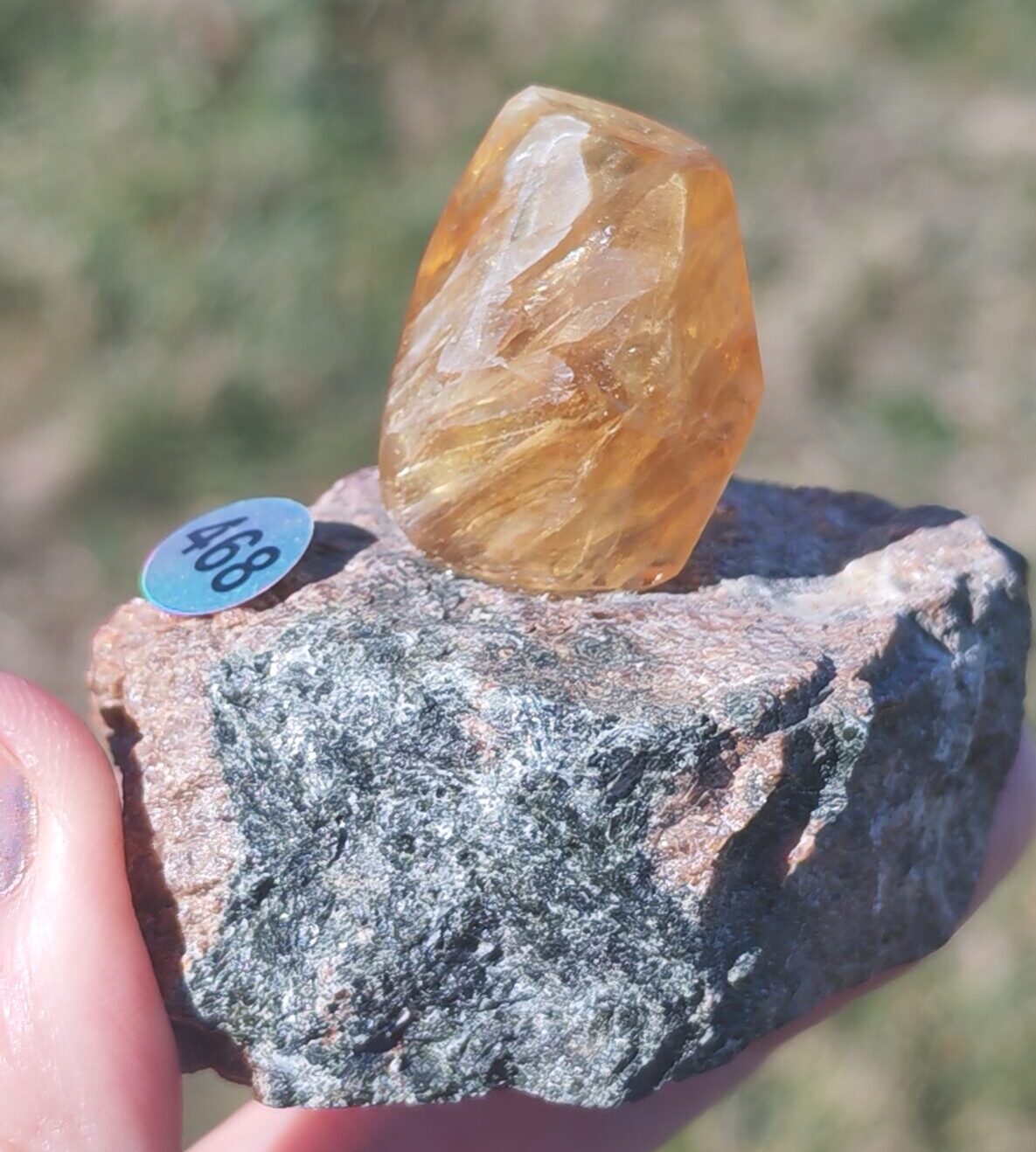 Fluorite couleur miel montrant ses structures internes sur une matrice verte et rosée avec la référence 468